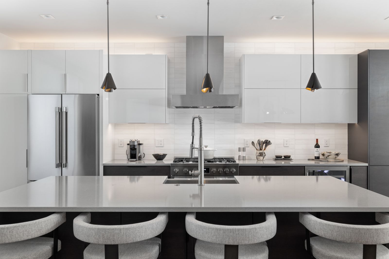 Clean modern kitchen with cleared counters, white cabinetry and pendant lights, ready for a real estate photo shoot