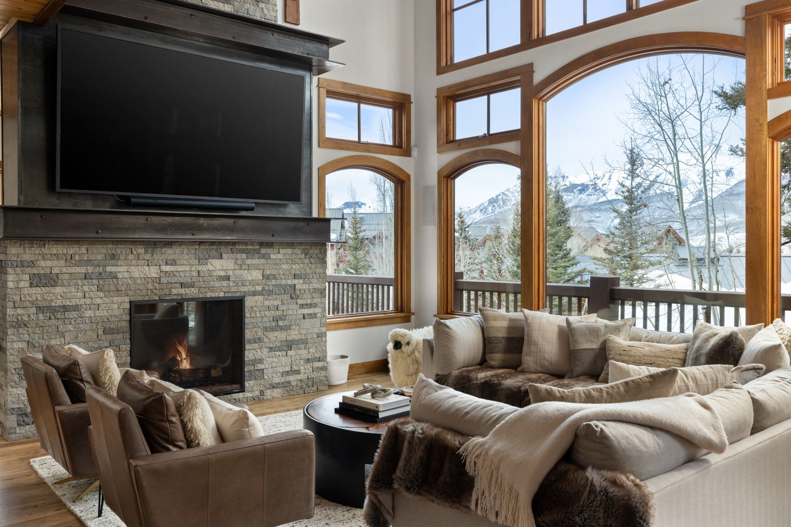 Great room with stone fireplace and floor-to-ceiling windows framing snowy peaks, Telluride architectural photography